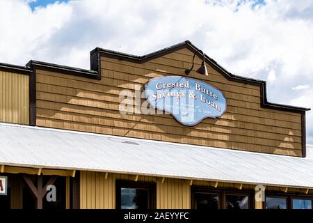 Mount Crested Butte, Stati Uniti d'America - 21 Giugno 2019: Colorado villaggio storico downtown in estate con il segno per Banco exterior Gunnison ramo di risparmio e prestito Foto Stock