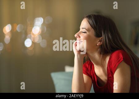 Profilo di donna felice la meditazione seduta su un divano nella notte a casa Foto Stock