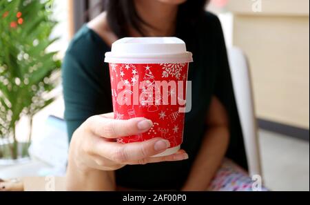 Donna che mantiene un rosso e bianco Natale foglio di modello Tazza da caffè Foto Stock