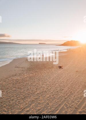 una coppia che ha la sua luna di miele, camminando lungo una spiaggia nelle hawaii mentre il tramonto Foto Stock