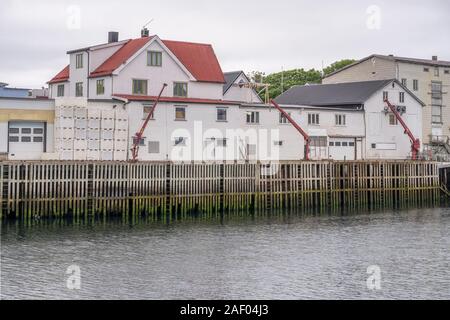 Circolo polare artico fjord cityscape del pittoresco villaggio mostra tradizionale stilt magazzino sul terrapieno, girato sotto la luminosa luce torbida a Haenningsvaer Foto Stock