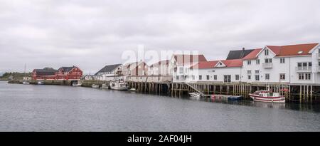 HENNINGSVAER, Norvegia - 13 Luglio 2019: Circolo Polare Artico fjord cityscape del pittoresco villaggio mostra di barche da pesca e le tradizionali palafitte a embankm Foto Stock