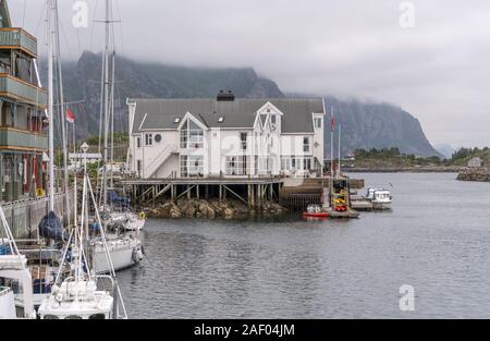 HENNINGSVAER, Norvegia - 13 Luglio 2019: Circolo Polare Artico fjord cityscape del pittoresco villaggio sotto nuvole basse sulla banchina con barche tradizionali e stilt h Foto Stock