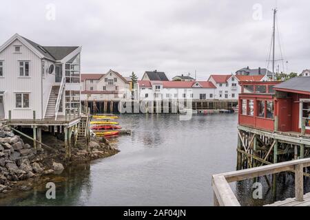 HENNINGSVAER, Norvegia - 13 Luglio 2019: Circolo Polare Artico fjord cityscape del pittoresco villaggio con i tradizionali palafitte , girato sotto il brillante paglierino torbido Foto Stock