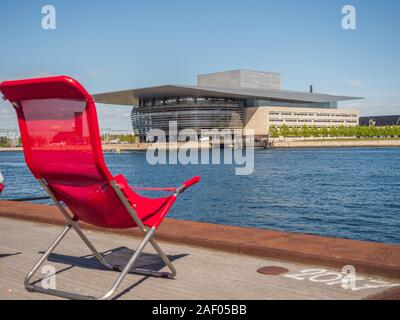 Copenhagen, Danimarca - 26 Aprile 2019: Rosso lettini con Copenaghen Opera House in background. Isola di Holmen Foto Stock