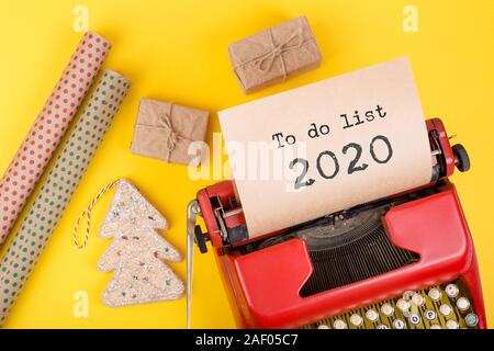 Concetto di vacanze - rosso nastri inchiostratori per macchine da scrivere con il testo "lista Da fare 2020', confezioni regalo e carta di avvolgimento su sfondo giallo Foto Stock