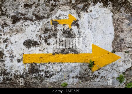 Quando una freccia gialla non è sufficiente, freccia gialla dipinta su una pietra, Camino de Santiago de Compostela, Spagna Foto Stock