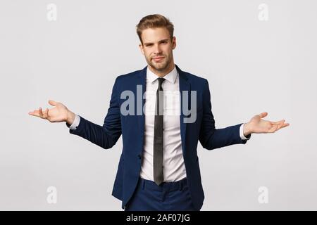 Non lo so. Sicuri e perplesso bello imprenditore con setole, taglio di capelli biondi, indossare tuta, diffondere le mani lateralmente e scrollare incerta, hanno Foto Stock