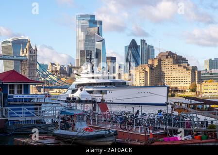 Barche e Superyacht Bravo Eugenia ormeggiata presso il Tower Bridge posti barca presso Downings strade sul Fiume Tamigi, Londra, Regno Unito. Tower Hotel e il quartiere finanziario Foto Stock