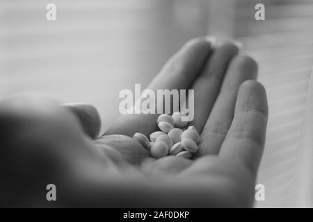 Medical pillole in mano umana closeup. Vitamine nel palmo di una persona. Foto in bianco e nero. Trattamento o farmaci. Foto Stock