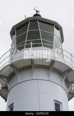 Faro più antico ancora operativo NZ, in ghisa dipinta di bianco con porta rossa. Costruito nel 1864, aperto nel 1865. A energia solare. Golfo di Hauraki, Auckland. Foto Stock