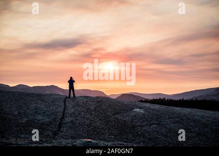 L'uomo stagliano contro il tramonto in montagna Foto Stock