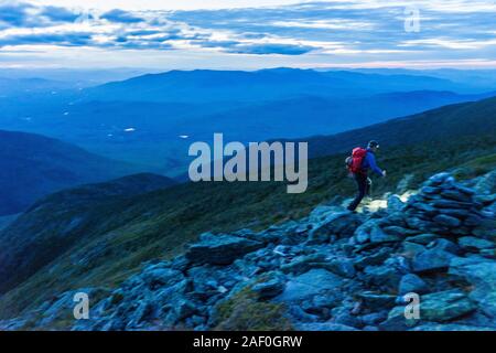 L'uomo escursionismo da proiettore lungo il sentiero roccioso in montagna Foto Stock