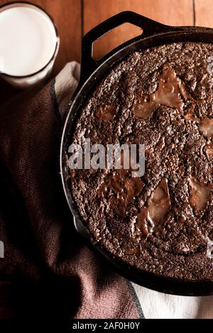 Caramello brownie dessert in una padella in ghisa con un bicchiere di latte Foto Stock