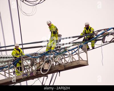 I tecnici al lavoro per sostituire i vecchi isolatori su un pilone in Barrow su Soar, Leicestershire, Regno Unito. Foto Stock