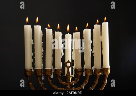 Candele accese in menorah su Hanukkah isolato su nero Foto Stock