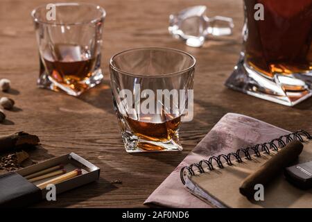 Bicchieri di brandy, sigari con mappa e pistacchi sul tavolo di legno Foto Stock