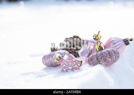 Rosa di Natale inverno - Palle di Natale con nastro sulla neve, vacanze invernali concetto. Natale palline dorate, pini e decorazioni di fiocchi di neve Foto Stock