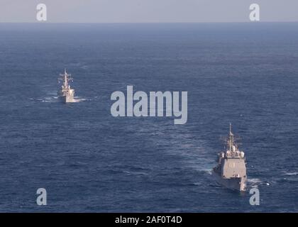 191129-N-OI558-1596 Mar Cinese Orientale (nov. 29, 2019) Il Arleigh Burke-class guidato-missile destroyer USS Barry (DDG 52), sinistra, vele in formazione con il Ticonderoga-class guidato-missili cruiser USS Shiloh (CG 67) durante un esercizio di manovra alla superficie di supporto del gruppo di azione delle operazioni. Shiloh è distribuita negli Stati Uniti 7 flotta area di operazioni a sostegno della sicurezza e della stabilità nella regione Indo-Pacifico. (U.S. Foto di Marina di Massa lo specialista di comunicazione di terza classe Chanel L. Turner) Foto Stock