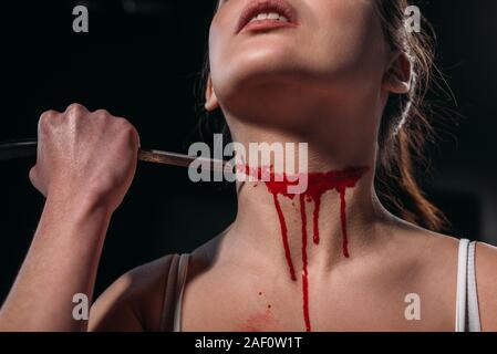 Vista ritagliata della donna di suicidarsi dalla gola di taglio con il rasoio isolato su nero Foto Stock