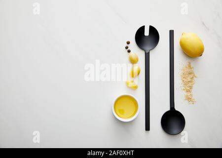 Vista superiore di olio di oliva con il succo di limone, pomodorini e siviera con cucchiaio su Sfondo marmo Foto Stock