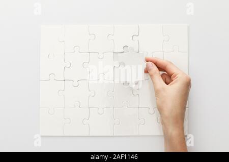 Vista ritagliata della donna completando puzzle su sfondo bianco Foto Stock
