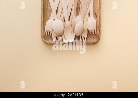 Vista superiore di forma rettangolare piatto in legno con forche, coltelli e cucchiai su sfondo beige Foto Stock