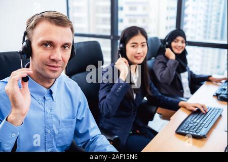 Gruppo di giovani professione operatore di call center agent con cuffie che lavorano in ufficio. Il telemarketing Business servizio persone concentrandosi su avente co Foto Stock
