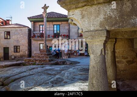 Combarro, Pontevedra, Galizia, Spagna : donne locali sedersi in una piccola piazza con una tipica cruzeiro croce di pietra nella tradizionale città vecchia di Foto Stock