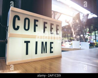 Tempo di caffè, testo in bianco scatola luminosa, decorazione sul tavolo di legno in una caffetteria all'aperto con sfondo spazio copia. Foto Stock