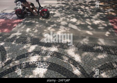 Balneario Camboriu, Santa Catarina, Brasile - 18 Novembre 2019: uomo alla guida di scooter elettrico attraverso un crosswalk in Atlantic Avenue Foto Stock