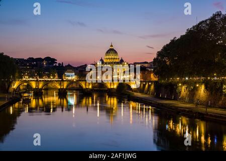 La Basilica Papale di San Pietro, Basilica di San Pietro e il Ponte Sant'Angelo, illuminata di notte, mirroring nel fiume Tevere Foto Stock