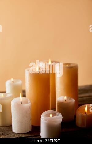 Close up di candele accese sul tavolo di legno sul beige Foto Stock