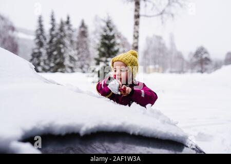 Ragazza spazzolando la neve da auto Foto Stock