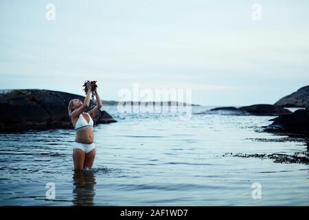 Donna in piedi in mare Foto Stock