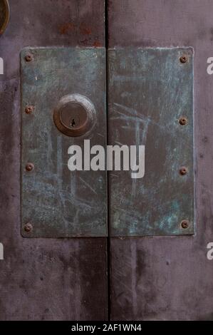 Porta Vecchia serratura con piastra di metallo di grandi dimensioni su viola porta in legno Foto Stock