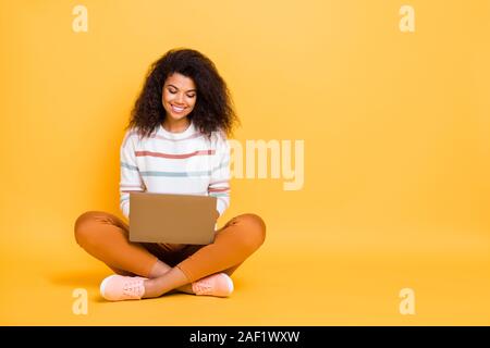 Ritratto di lei bella attraente bella Allegro vivace mossi dai capelli ragazza seduta in lotus pongono la digitazione di lavorare studiare in remoto isolato sul luminoso Foto Stock