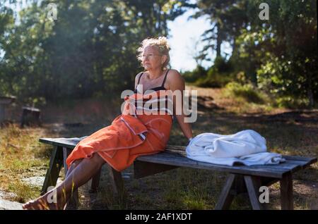 Donna avvolta in asciugamano rilassante sul banco di lavoro Foto Stock