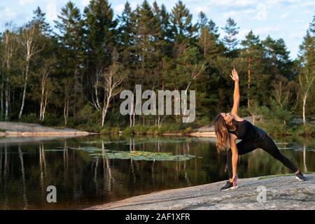 Donna al lago facendo yoga Foto Stock