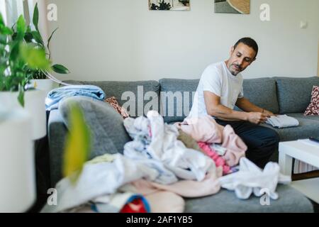 Uomo abiti di piegatura sul divano Foto Stock