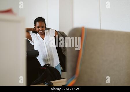 Donna sorridente mettendo su blazer Foto Stock