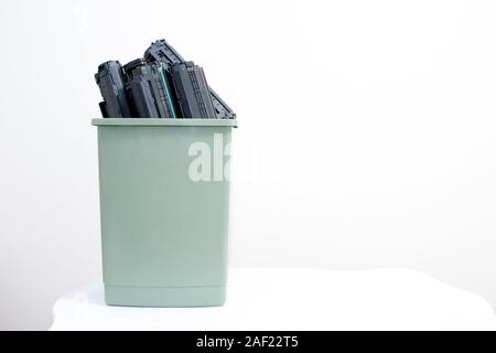 Trascorso le cartucce vengono impilati in un contenitore su uno sfondo bianco. Il concetto del problema dello smaltimento delle sostanze chimiche nocive spreco di office equipmen Foto Stock