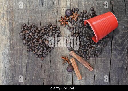 A forma di cuore in chicchi di caffè e una fuoriuscita di red cup con una spezie-NOZIONE valentine Foto Stock