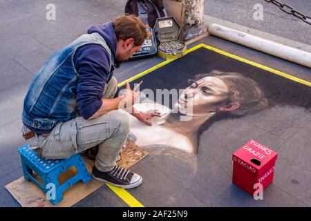 Un artista di strada è dipinto il ritratto di una donna su una passerella Foto Stock