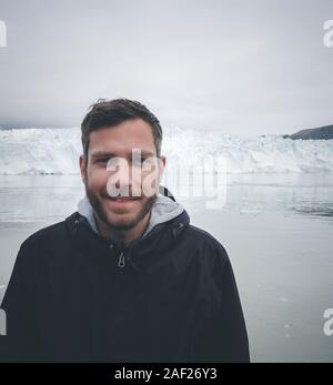 Giovani viaggiatori soggiorno turistico in piedi di fronte del ghiacciaio enorme muro di ghiaccio. Icebergs Ilulissat. Jakobshaven Eqip Sermia Glacier ghiacciaio di Eqi Sermia in Foto Stock