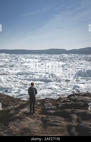 La gente seduta in piedi di fronte del ghiacciaio enorme muro di ghiaccio. Icebergs Ilulissat. Jakobshaven Eqip Sermia Glacier ghiacciaio di Eqi Sermia in Groenlandia chiamato Foto Stock