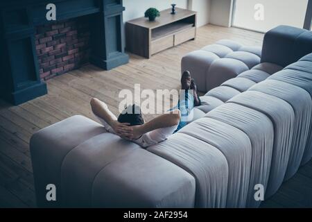 Brunette guy sdraiato sul divano confortevole appoggio libero di spesa tempo libero giorno daydream a spazio aperto posto di lavoro della stazione di mattoni industriali loft interni casa Foto Stock