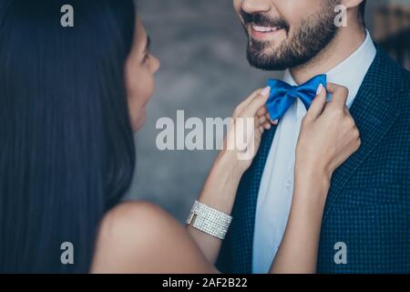 Foto ritagliata di due chic gente giovane ragazzo cerca signora che il fissaggio avendo cura di blu elegante bow tie miglior coppia alla festa di compleanno di classe di usura Foto Stock