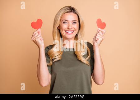 Foto di allegro carino carina positivo contenti lieti ragazza sorridente toothily verde che indossa la t-shirt tenendo due piccoli cuori che ha ricevuto da Foto Stock