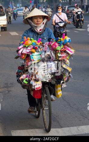 Ho Chi Minh City, Vietnam-October 29th 2013: un gingillo venditore cavalcare la sua bicicletta attraverso l'Ho Chi Minh traffico. Le biciclette sono state sostituite dal motore Foto Stock